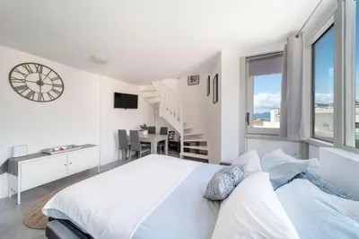 a white bedroom with a large bed and a staircase at Duplex centre de Cannes - terrasse, sunset & pool in Cannes