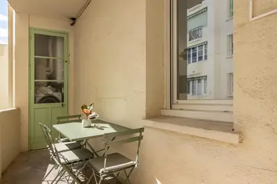 a table and chairs on a balcony with a window at Elégant et moderne T4 à 100M de La Croisette in Cannes