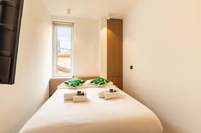 a bedroom with a large white bed with green pillows at Elégant et moderne T4 à 100M de La Croisette in Cannes