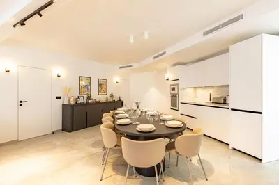 a dining room with a table and chairs and a kitchen at Elégant et moderne T4 à 100M de La Croisette in Cannes