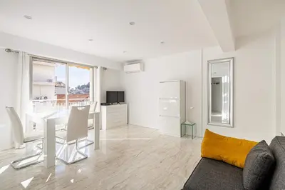 a white living room with a table and a couch at LE LOUIS BLANC avec balcon en plein centre-ville in Cannes