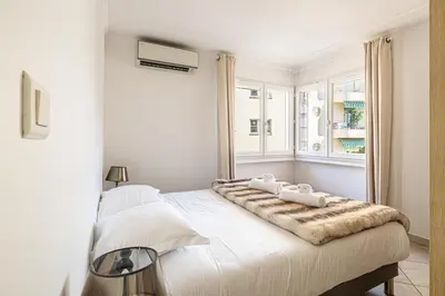 a white bedroom with a large bed with two pillows on it at 78 LERINS - Bel appartement 2 chambres sur la Croisette in Cannes