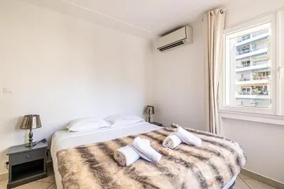 a white bedroom with a bed with towels on it at 78 LERINS - Bel appartement 2 chambres sur la Croisette in Cannes