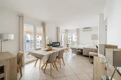 a kitchen and living room with a table and chairs at 78 LERINS - Bel appartement 2 chambres sur la Croisette in Cannes