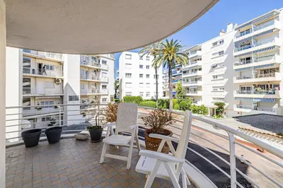 a balcony with two chairs and a table and some buildings at 78 LERINS - Bel appartement 2 chambres sur la Croisette in Cannes