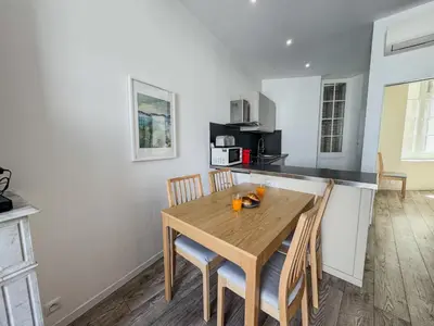 a kitchen and dining room with a wooden table and chairs at RED DOOR Forville Market View in Cannes
