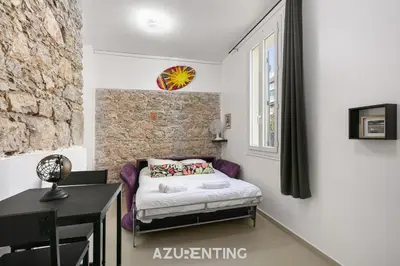 a table and two chairs in front of a stone wall at Azurenting - Bastide Alba - Studio - Terrasse in Cannes