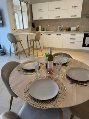 a table with plates and glasses and a bottle of wine at Magnifique T2 avec grande terrasse in Le Cannet