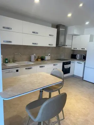 a kitchen with white cabinets and a table and chairs at Magnifique T2 avec grande terrasse in Le Cannet