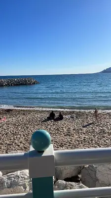 a beach with people laying on the sand and the water at La Palme studio in Cannes