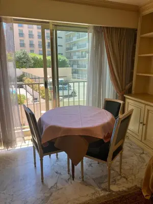 a table and chairs in a room with a window at La Palme studio in Cannes
