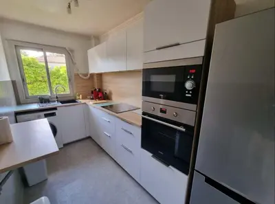 a kitchen with white cabinets and a black appliance at Appartement entier cosy au calme in Le Cannet
