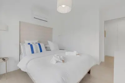 a white bedroom with a white bed with towels on it at 2 chambres - Grand balcon - à 1 min de la plage in Cannes