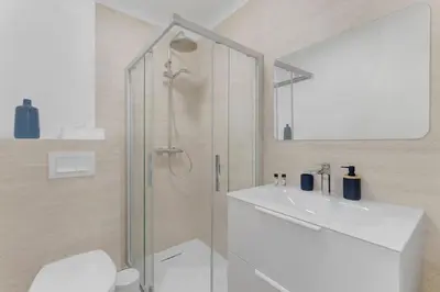 a white bathroom with a shower and a sink at 2 chambres - Grand balcon - à 1 min de la plage in Cannes