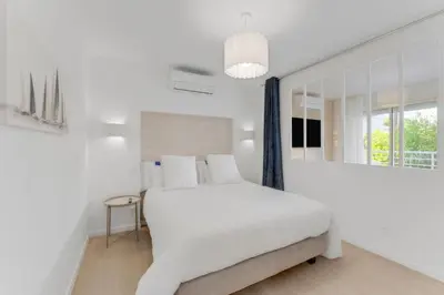 a white bedroom with a white bed and a mirror at 2 chambres - Grand balcon - à 1 min de la plage in Cannes