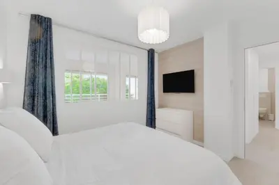 a white bedroom with a large bed and a television at 2 chambres - Grand balcon - à 1 min de la plage in Cannes