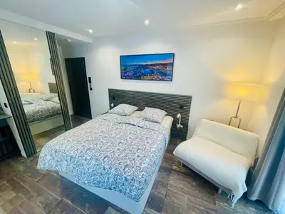 a bedroom with a bed and a chair and a mirror at Le Pinson Mignon Cannes Carre d Or in Cannes