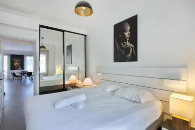 a bedroom with a large white bed and a mirror at YELLOW DUBOY D'ANGERS 2 Bedrooms in Cannes
