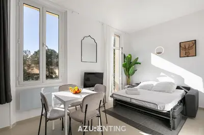 a building with green shutters and chairs on a balcony at Azurenting - Bastide Mira - 1 chambre - Balcon in Cannes