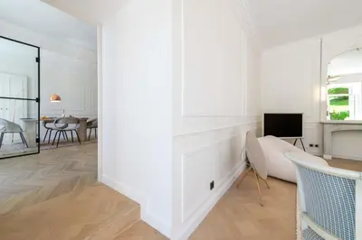 a white living room with a couch and a tv at Garden-Level Apartment in Bourgeois Residence Near Croisette & Beaches in Cannes