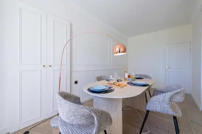 a white dining room with a table and chairs at Garden-Level Apartment in Bourgeois Residence Near Croisette & Beaches in Cannes