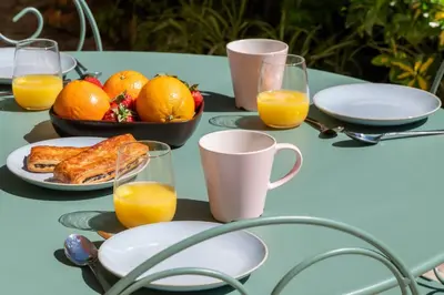 a table with plates of food and glasses of orange juice at Garden-Level Apartment in Bourgeois Residence Near Croisette & Beaches in Cannes