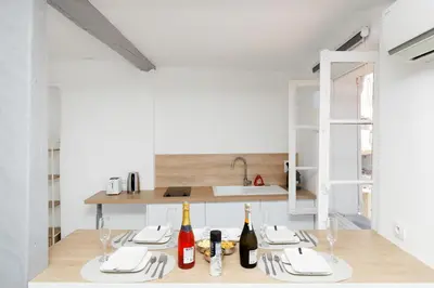 a kitchen with white walls and a table with wine bottles at Renoveted studio - Central - AC in Cannes
