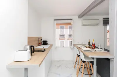 a kitchen with white walls and a counter with stools at Renoveted studio - Central - AC in Cannes