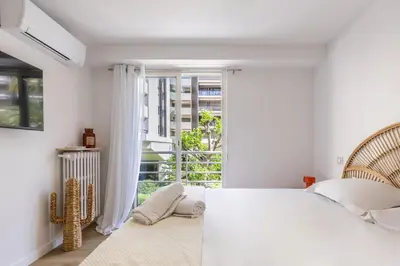 a white bedroom with a bed and a large window at LB Vacation Rentals I Beautiful 2BR Apt, Renovated in 2025, La Croisette, Minutes from Beach and Palais in Cannes