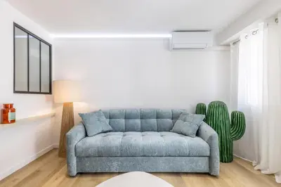 a living room with a blue couch and a cactus at LB Vacation Rentals I Beautiful 2BR Apt, Renovated in 2025, La Croisette, Minutes from Beach and Palais in Cannes