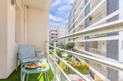 a balcony with a table with a plate of food at LB Vacation Rentals I Beautiful 2BR Apt, Renovated in 2025, La Croisette, Minutes from Beach and Palais in Cannes