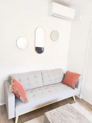 a white couch in a living room with red pillows at Studio au calme 100 mètres de la croisette in Cannes