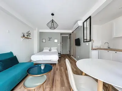 a living room with a couch and a bed and a table at Studio proche gare, balcon in Cannes