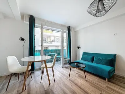 a living room with a blue couch and a table at Studio proche gare, balcon in Cannes