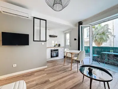 a living room with a glass table and a kitchen at Studio proche gare, balcon in Cannes