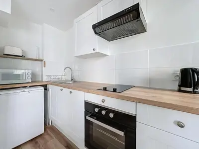 a kitchen with white cabinets and a black appliance at Studio proche gare, balcon in Cannes