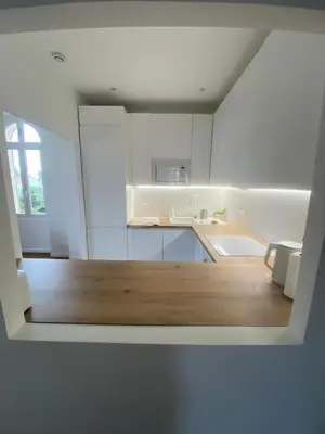 a kitchen with white cabinets and a wooden floor at Lisa Appartement de charme in Cannes