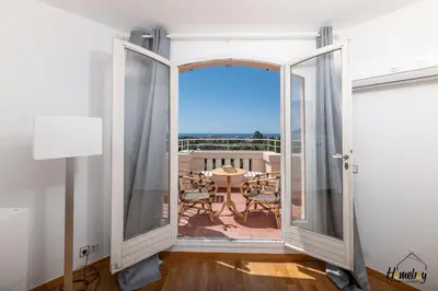 a room with doors open to a balcony with a table at La Gloriette Azur piscine sauna vue mer in Cannes