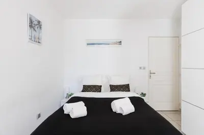 a white bedroom with a large bed with two pillows at Cannes Maria YourHostHelper in Cannes