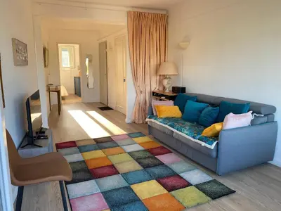 a living room with a blue couch and a colorful rug at Appartement moderne avec vue mer à Cannes in Cannes