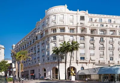 a large white building with palm trees in front of it at Palais Miramar Croisette 2 BRD Gold Suite in Cannes