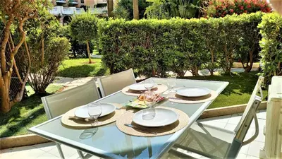a glass table with hats and plates on it at Beachfront 4 people 2 swimming pool in Cannes
