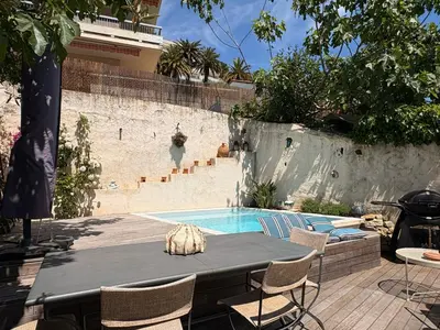a patio with a table and chairs and a swimming pool at Charmante maison de village avec petite piscine privée in Le Cannet