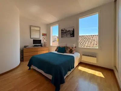 a bedroom with a bed and two windows at Charmante maison de village avec petite piscine privée in Le Cannet