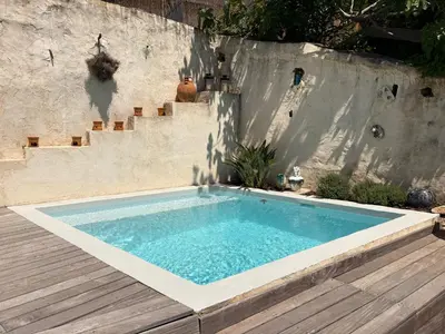 a swimming pool in a backyard with a wooden deck at Charmante maison de village avec petite piscine privée in Le Cannet
