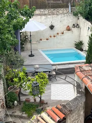 a swimming pool with an umbrella on a wooden deck at Charmante maison de village avec petite piscine privée in Le Cannet
