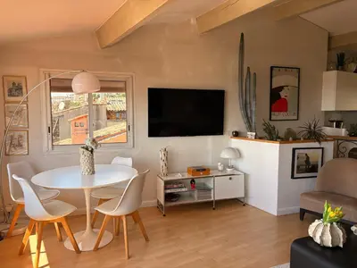 a living room with a white table and a tv at Charmante maison de village avec petite piscine privée in Le Cannet