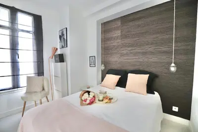 a bedroom with a white bed with a chair and a table at Chic 1-bedroom apartment steps away from La Croisette in Cannes