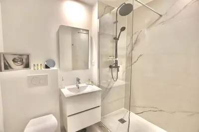 a white bathroom with a shower and a sink at Chic 1-bedroom apartment steps away from La Croisette in Cannes