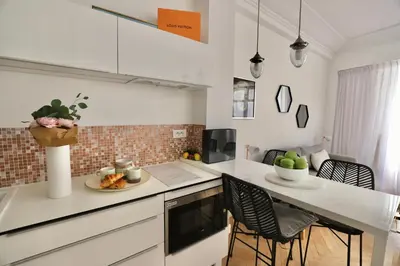 a kitchen with white counters and a table with chairs at Chic 1-bedroom apartment steps away from La Croisette in Cannes